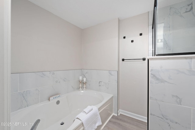 bathroom featuring baseboards, a bath, and wood finished floors
