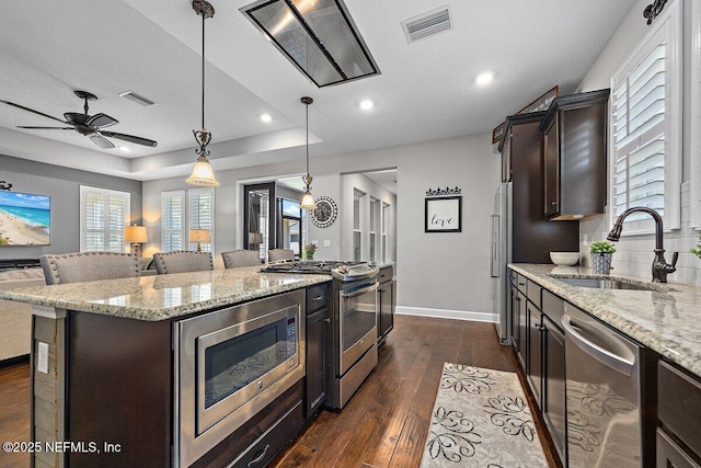 135 Outpost Trl, Ponte Vedra, FL 32081 - kitchen with stainless steel appliances, a sink, dark brown cabinetry, a center island, and dark wood-style flooring