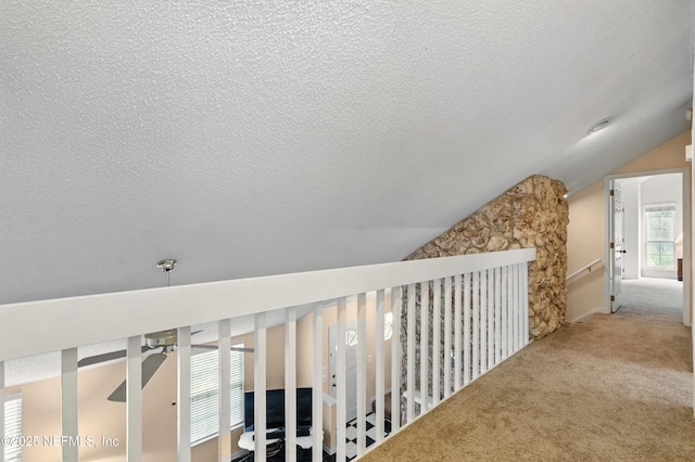 hall featuring carpet floors, a textured ceiling, and lofted ceiling