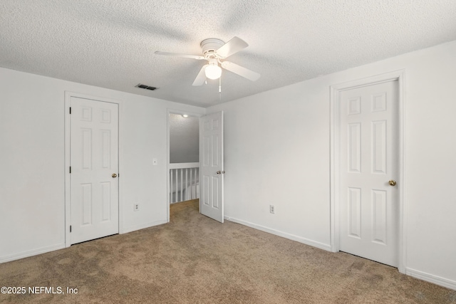 unfurnished bedroom with visible vents, a textured ceiling, carpet floors, and baseboards