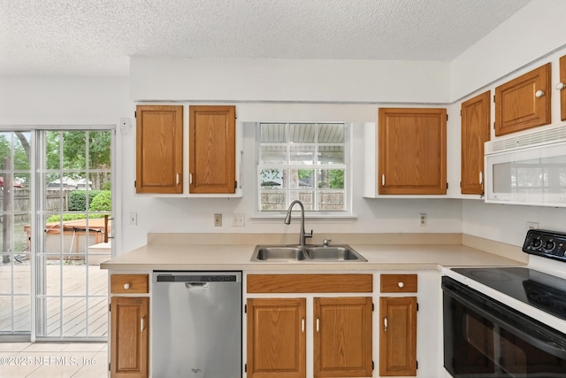 kitchen with a textured ceiling, dishwasher, a sink, white microwave, and electric stove