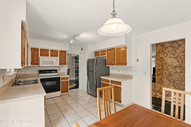 kitchen with range with electric stovetop, a sink, light countertops, white microwave, and freestanding refrigerator