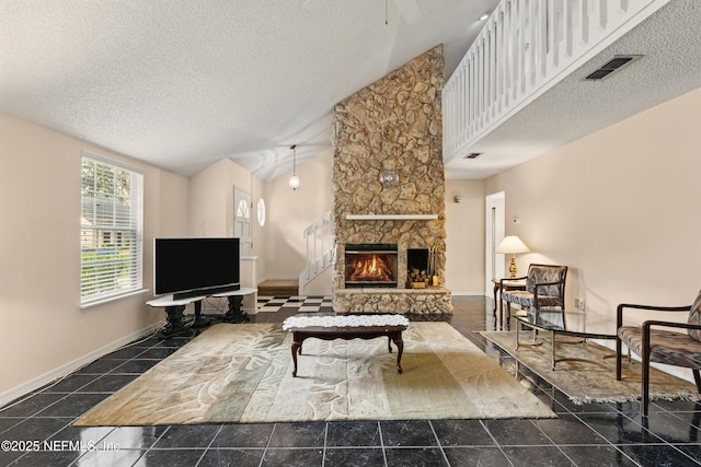 living room with a textured ceiling, high vaulted ceiling, a stone fireplace, a ceiling fan, and visible vents
