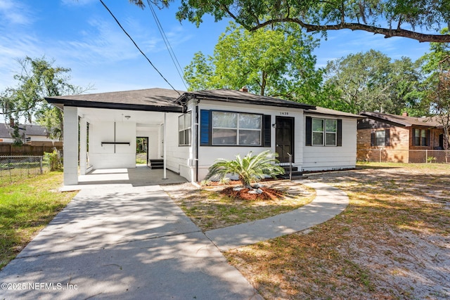 bungalow featuring entry steps, fence, an attached carport, and concrete driveway