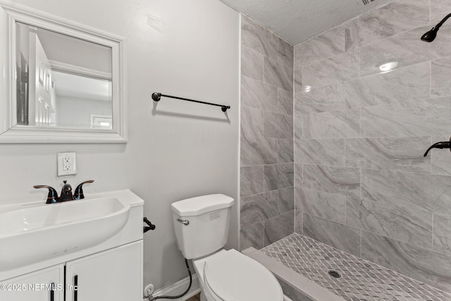full bathroom with toilet, a textured ceiling, a tile shower, and vanity