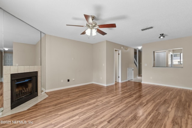 3801 Crown Point Rd Unit 1032, Jacksonville, FL 32257 - unfurnished living room with visible vents, baseboards, light wood-type flooring, a tiled fireplace, and a ceiling fan
