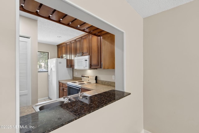 3801 Crown Point Rd Unit 1032, Jacksonville, FL 32257 - kitchen with a sink, white appliances, a textured ceiling, dark stone counters, and baseboards