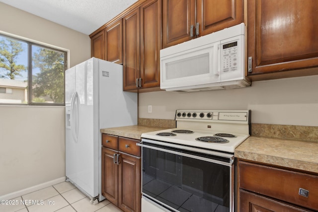 3801 Crown Point Rd Unit 1032, Jacksonville, FL 32257 - kitchen with white appliances, baseboards, light countertops, brown cabinets, and light tile patterned floors