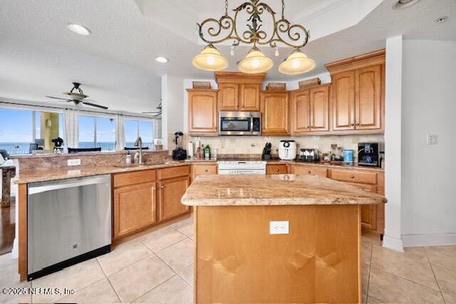 230 N Serenata Dr Unit 711, Ponte Vedra Beach, FL 32082 - kitchen with appliances with stainless steel finishes, light stone counters, a sink, a peninsula, and a kitchen island
