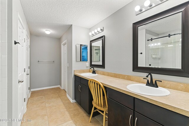 228 Gladstone Ct, Saint Johns, FL 32259 - bathroom with a textured ceiling, a shower stall, tile patterned flooring, double vanity, and baseboards