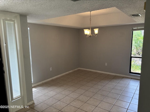 empty room with a notable chandelier, a textured ceiling, baseboards, light tile patterned floors, and visible vents
