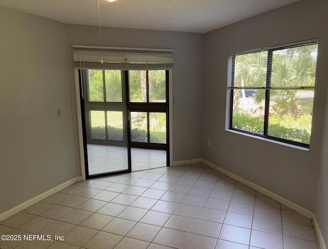 unfurnished room with light tile patterned floors, baseboards, plenty of natural light, and a textured ceiling