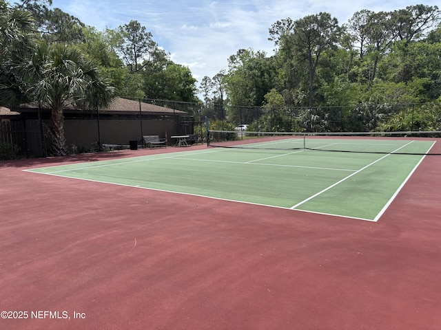view of tennis court featuring community basketball court and fence