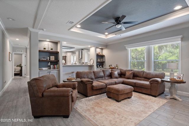 living room featuring visible vents, ornamental molding, wood finished floors, baseboards, and a ceiling fan