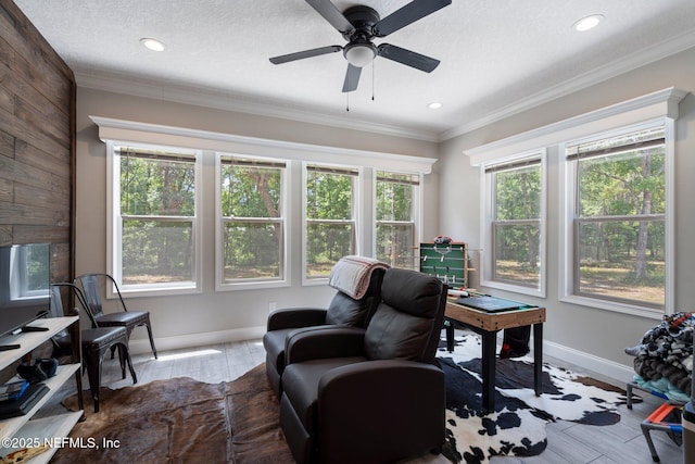 interior space featuring crown molding, baseboards, ceiling fan, and wood finished floors
