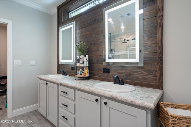 bathroom featuring crown molding, double vanity, baseboards, and a sink