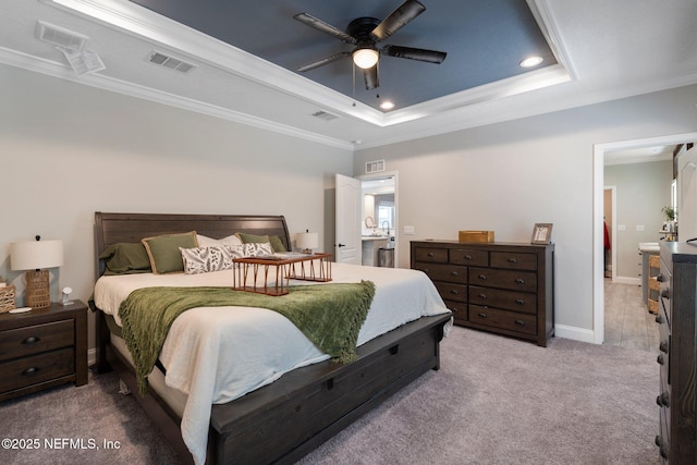 bedroom with crown molding, a tray ceiling, and visible vents