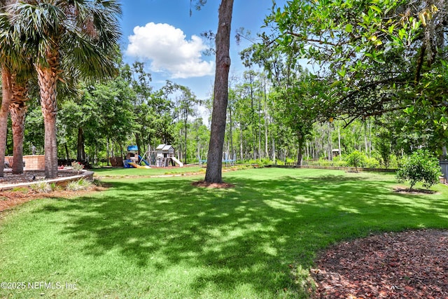 view of grassy yard featuring view of wooded area