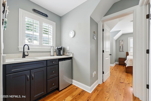 bar featuring a sink, light wood-type flooring, and baseboards