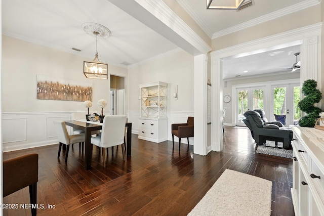 dining space featuring dark wood-style flooring, a chandelier, crown molding, and a wainscoted wall