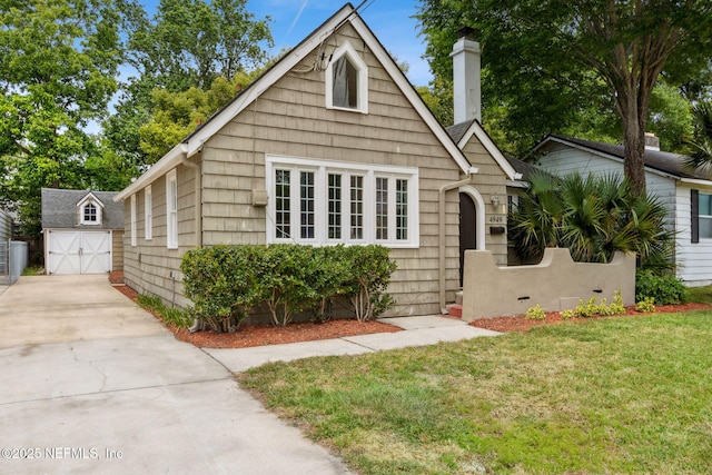 4949 Fremont St, Jacksonville, FL 32210 - bungalow-style house featuring driveway, a chimney, an outbuilding, a detached garage, and a front lawn