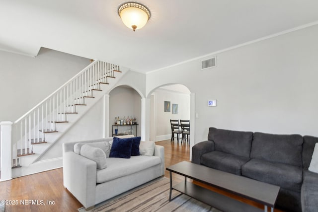 4949 Fremont St, Jacksonville, FL 32210 - living room with visible vents, ornamental molding, wood finished floors, stairway, and arched walkways
