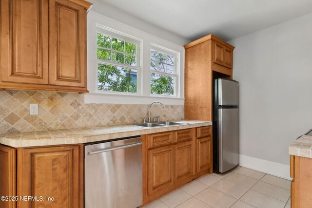 4949 Fremont St, Jacksonville, FL 32210 - kitchen with decorative backsplash, appliances with stainless steel finishes, a sink, light tile patterned floors, and light countertops