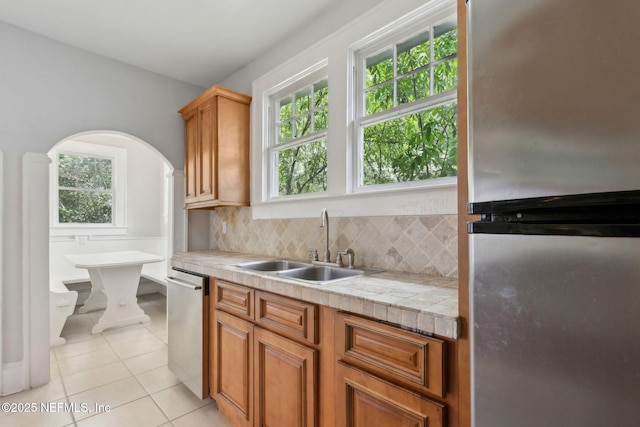 4949 Fremont St, Jacksonville, FL 32210 - kitchen featuring appliances with stainless steel finishes, a sink, light countertops, decorative backsplash, and light tile patterned floors