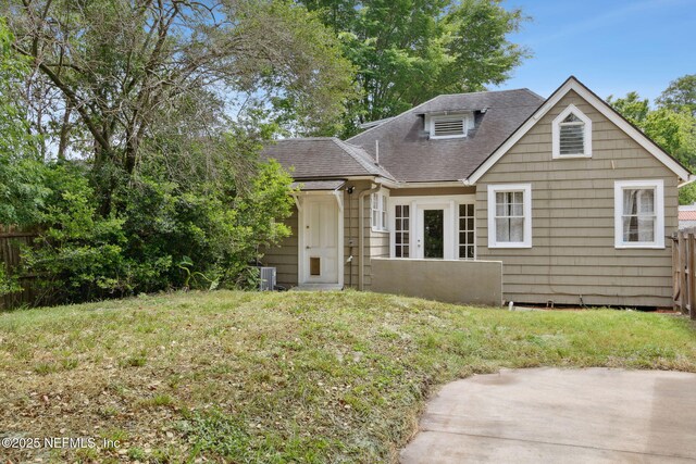 4949 Fremont St, Jacksonville, FL 32210 - bungalow-style home with a front lawn, fence, a shingled roof, central AC unit, and a patio area