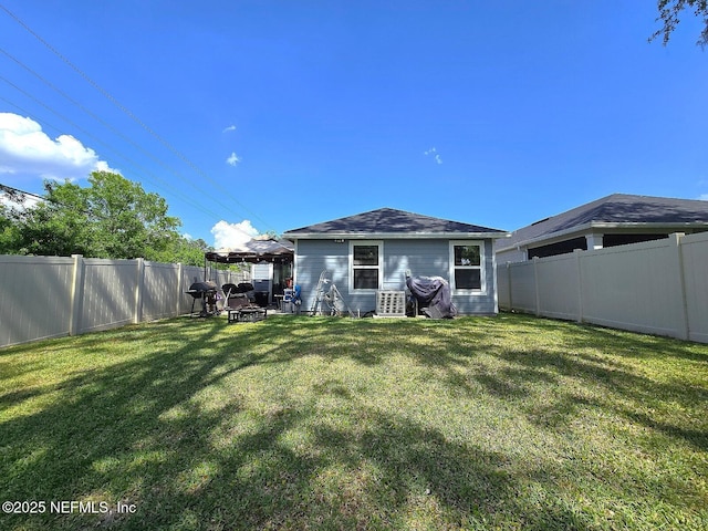 back of house featuring a lawn and a fenced backyard