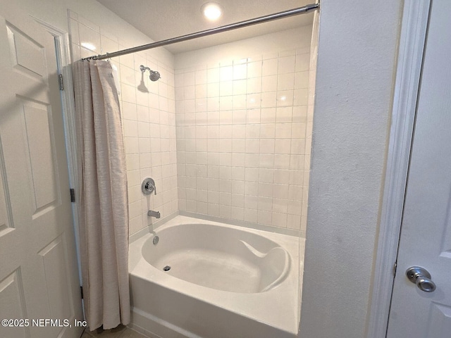 full bathroom with a textured wall and shower / tub combo with curtain