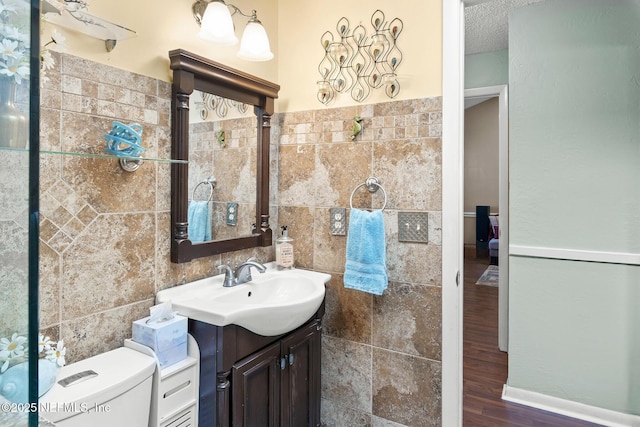 bathroom with vanity, wood finished floors, toilet, and tile walls