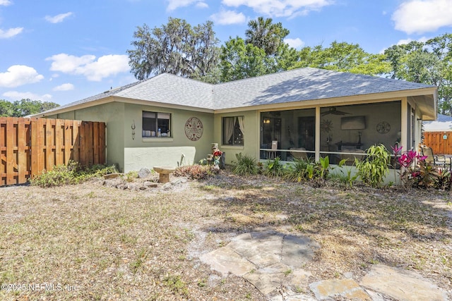 rear view of house with fence, ceiling fan, a sunroom, and roof with shingles