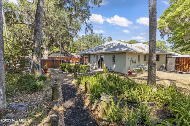 rear view of property featuring fence, a patio area, and stucco siding