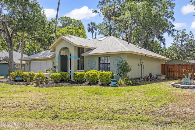 view of front facade featuring stucco siding, a front lawn, roof with shingles, and fence