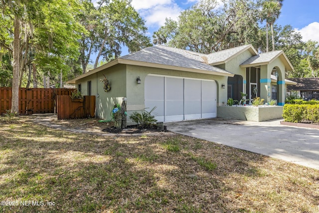view of property exterior featuring fence, a garage, driveway, and stucco siding