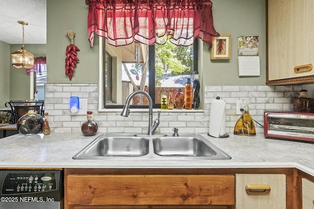 kitchen with a sink, light countertops, decorative backsplash, and dishwasher