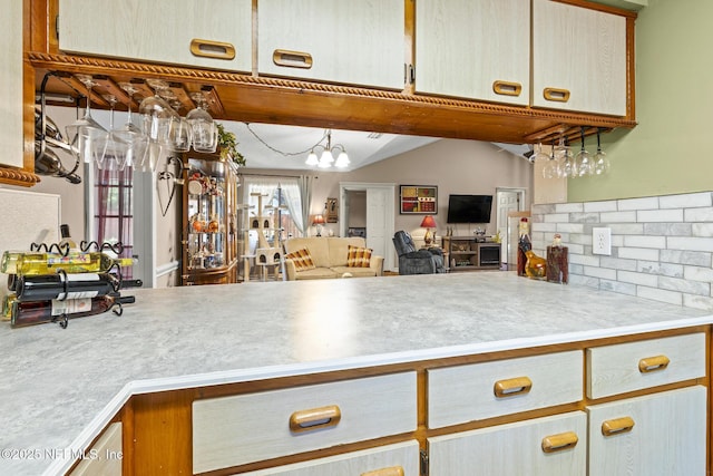 kitchen with light countertops, a notable chandelier, open floor plan, and tasteful backsplash