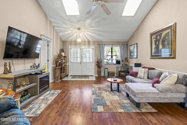 living room with a ceiling fan, a skylight, wood finished floors, and high vaulted ceiling