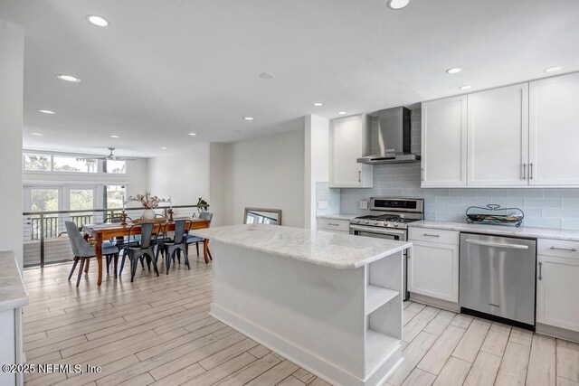 2325 Seminole Rd, Atlantic Beach, FL 32233 - kitchen with open shelves, appliances with stainless steel finishes, light wood finished floors, wall chimney exhaust hood, and decorative backsplash