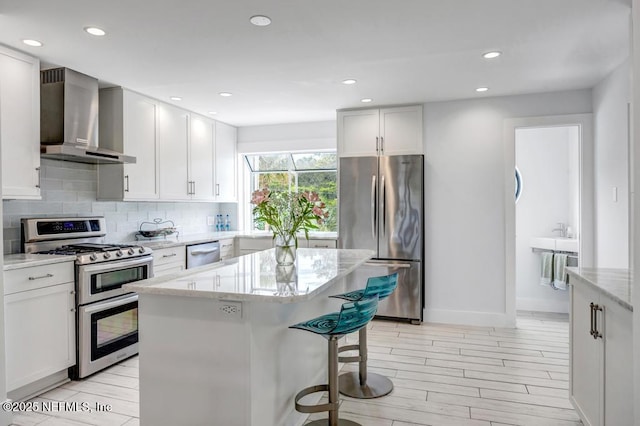 2325 Seminole Rd, Atlantic Beach, FL 32233 - kitchen featuring light stone countertops, a center island, backsplash, wall chimney range hood, and stainless steel appliances