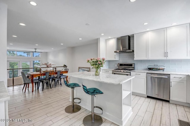 2325 Seminole Rd, Atlantic Beach, FL 32233 - kitchen with light wood-type flooring, wall chimney range hood, appliances with stainless steel finishes, and decorative backsplash