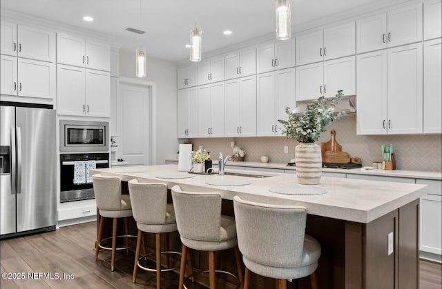 462 Hillendale Cir, Saint Johns, FL 32259 - kitchen with appliances with stainless steel finishes, a sink, a kitchen island with sink, light countertops, and backsplash