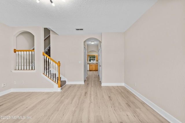 1879 Lago Del Sur Dr, Middleburg, FL 32068 - empty room featuring a textured ceiling, visible vents, arched walkways, baseboards, and light wood finished floors