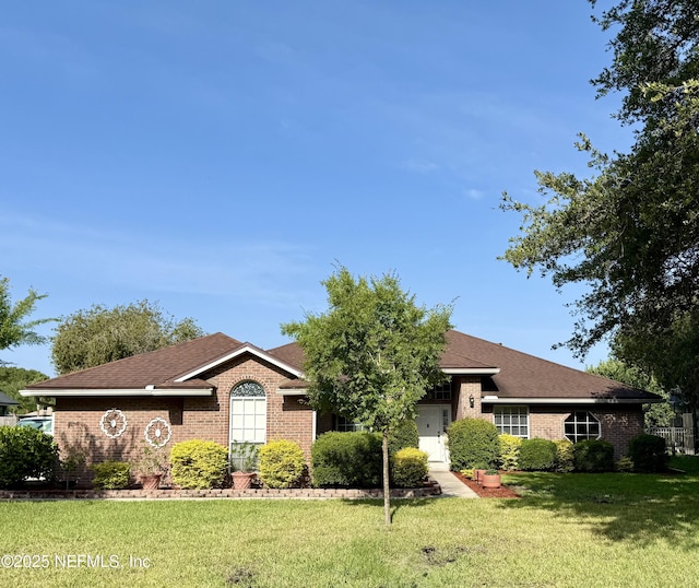 ranch-style house featuring brick siding, a front lawn, and roof with shingles