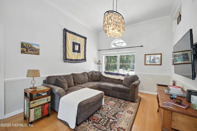 living area with ornamental molding, wood finished floors, and a chandelier