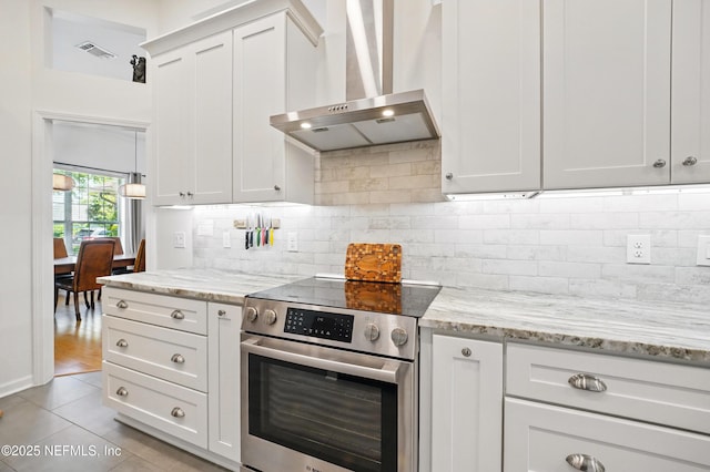 kitchen featuring light stone countertops, wall chimney exhaust hood, light tile patterned floors, electric stove, and backsplash