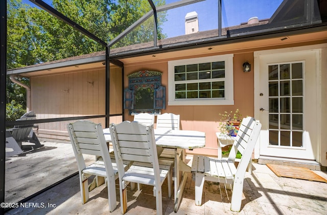 view of patio featuring glass enclosure and outdoor dining area