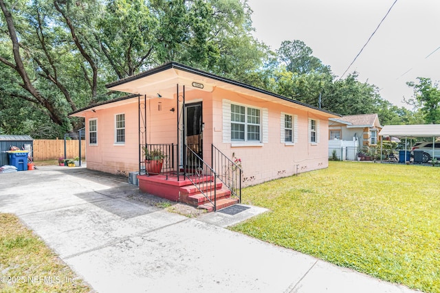 5545 Silverdale Ave, Jacksonville, FL 32209 - view of front of property with fence, concrete block siding, a front yard, concrete driveway, and an outdoor structure