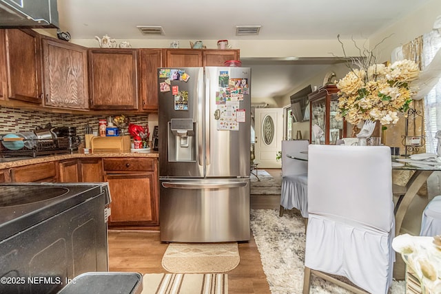 5545 Silverdale Ave, Jacksonville, FL 32209 - kitchen featuring light wood-style floors, appliances with stainless steel finishes, brown cabinetry, and visible vents